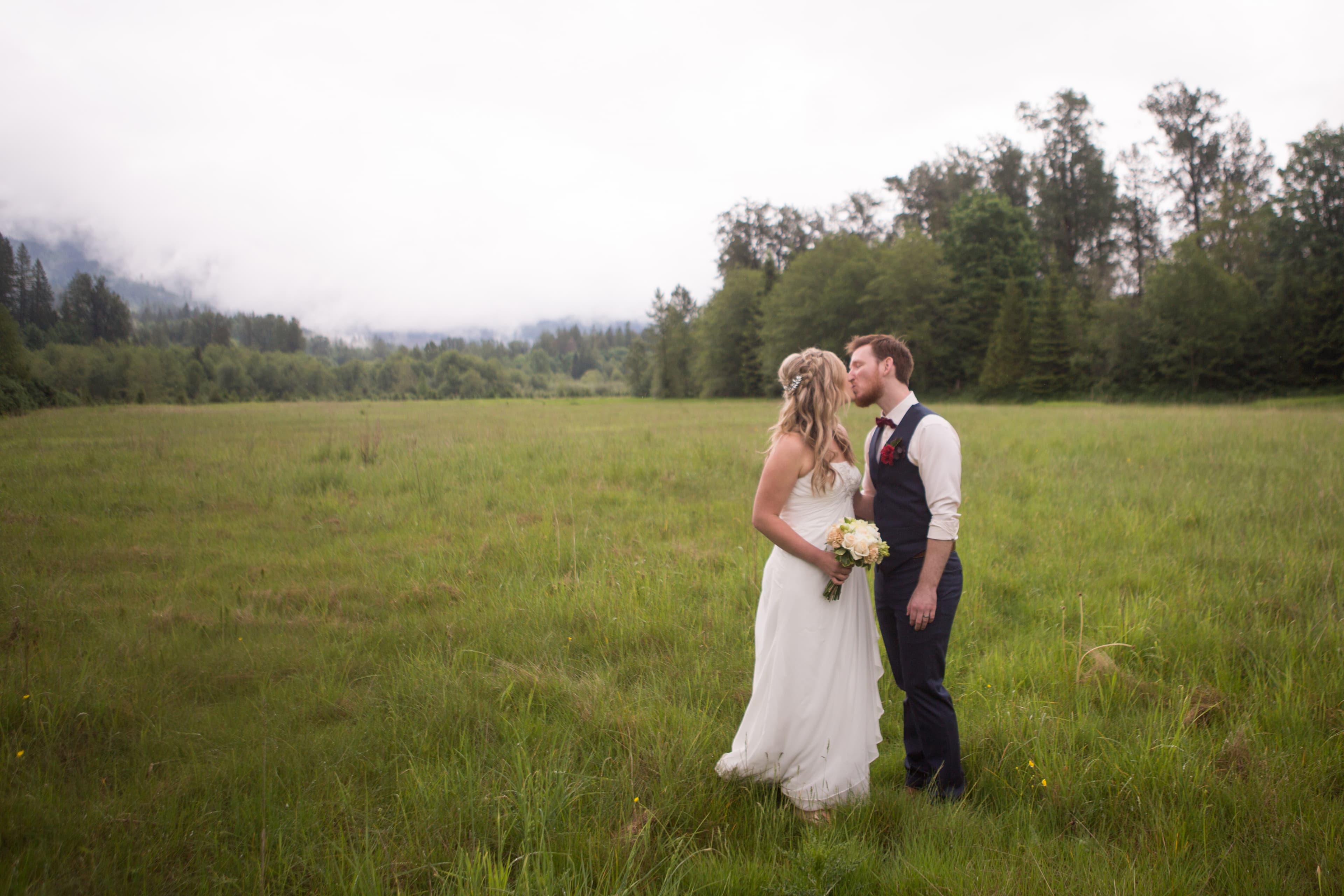 a bride and groom kissing in a field